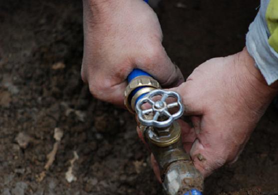 Hands connecting an underground pipe valve