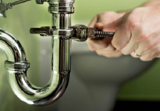 Chrome P-trap being tightened under a sink